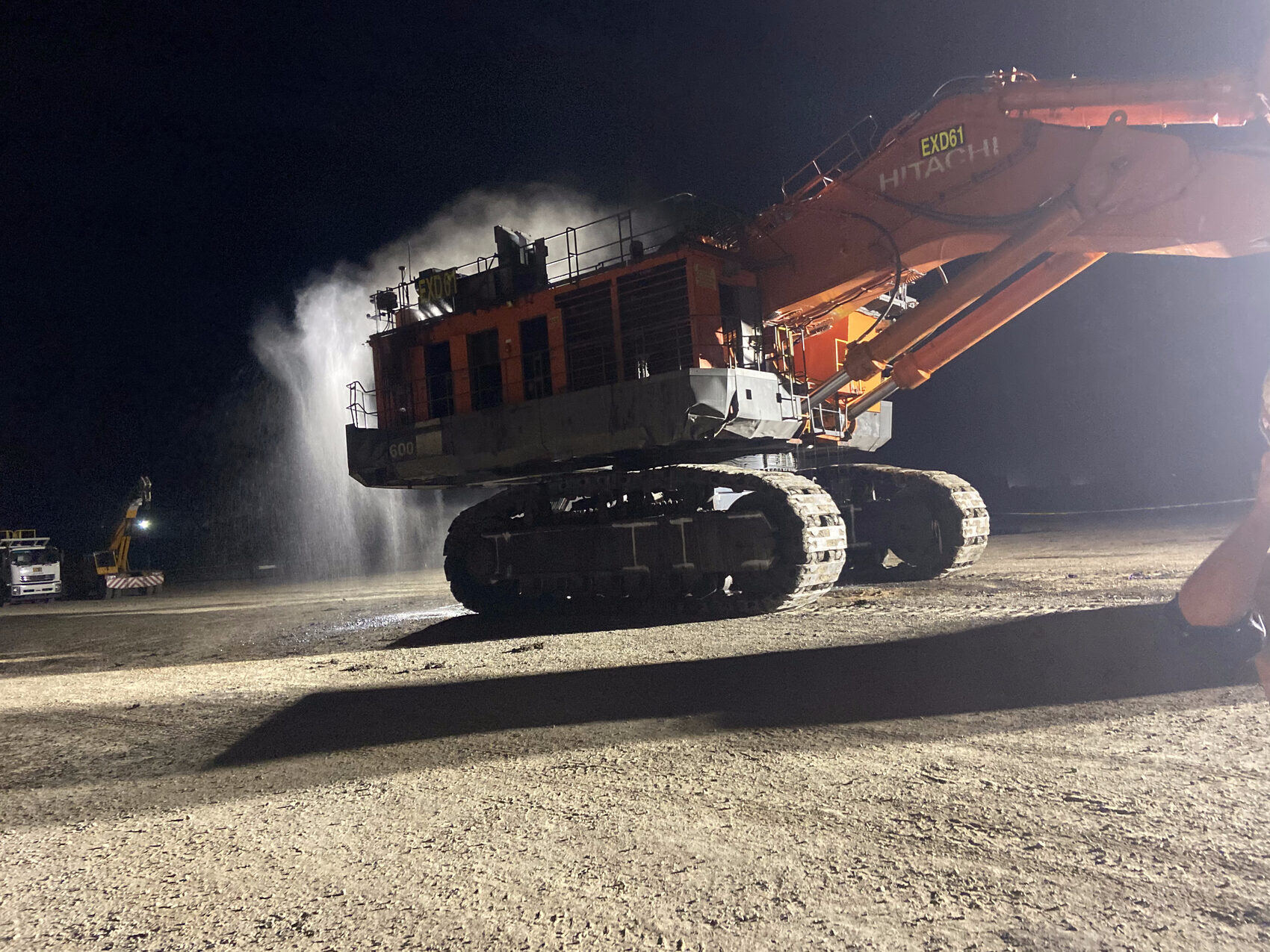 Hitachi EX excavator at night with water blowing out of the coolers during a service