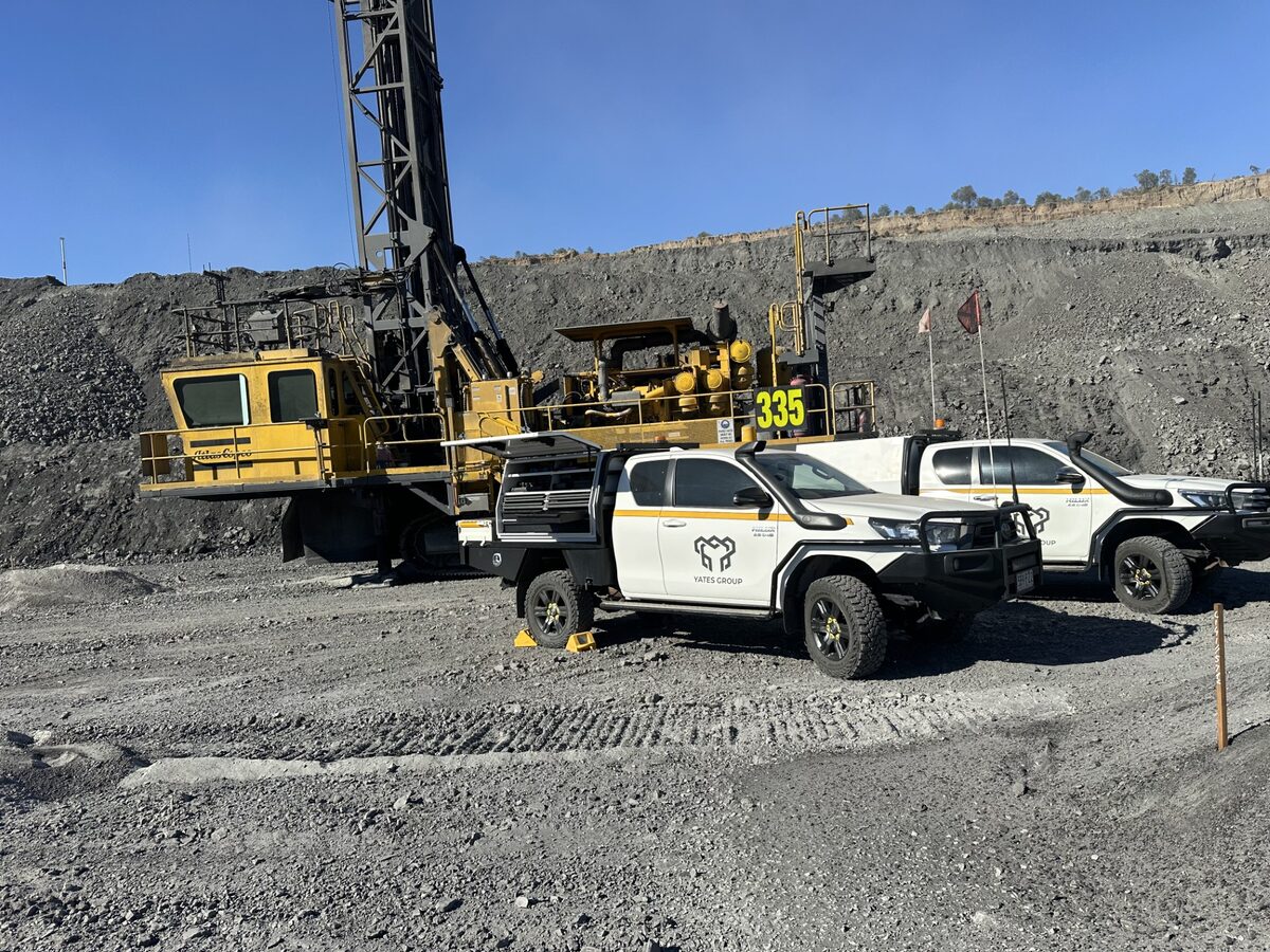 Blast-hole drill rig on a mine bench with Yates Group utes